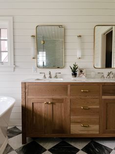 a bathroom with black and white checkered flooring, two large mirrors on the wall