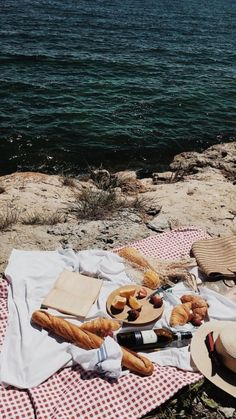 a picnic with bread and wine on a blanket near the water's edge,