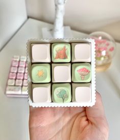 a hand holding a box of chocolates with trees and stars on the top in front of a keyboard