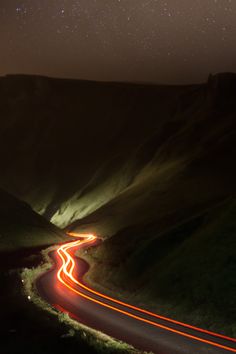 a long exposure shot of a road at night with the stars in the sky above