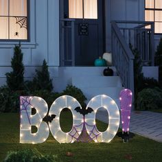 the word boo spelled out in front of a house with halloween decorations and bats on it