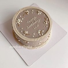 a birthday cake with white frosting and flowers on the top is sitting on a card