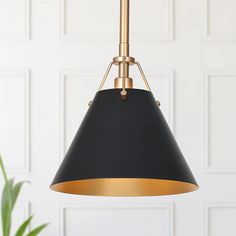 a black and gold pendant light hanging from a ceiling in front of a white wall