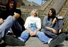 three young men sitting on the ground next to each other