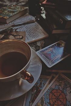 a cup of coffee sitting on top of a saucer next to tarot cards