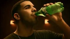 a man is drinking from a green bottle