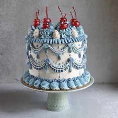 a blue and white cake with cherries on top