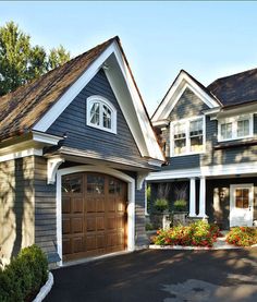 a large house with two garages on each side and flowers in the front yard