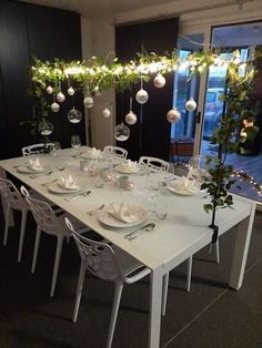 a dining room table is set with white dishes and place settings