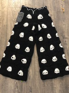 a pair of black and white knitted pants with skulls on them, sitting on a wood floor