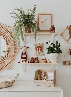 a white dresser topped with lots of shelves filled with potted plants and other items