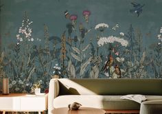 a living room scene with focus on the couch and wallpaper that has birds flying over it