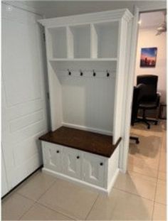 an empty room with white cabinets and wooden bench in the corner, next to a black chair