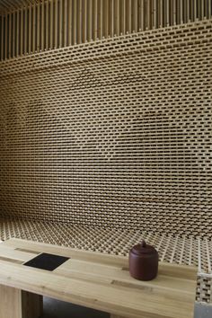 a table with a vase on it in front of a wall made out of bamboo sticks