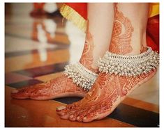 the legs and feet of a woman with henna tattoos on their feet are adorned with jewels