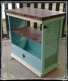 a blue and white cabinet sitting on top of a cement ground next to a fence