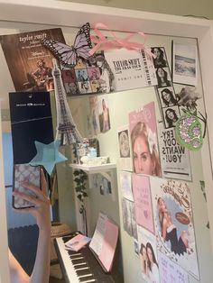 a woman holding a book in front of a wall covered with pictures and magnets