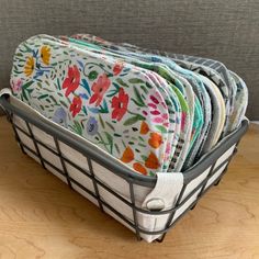 a basket filled with lots of cloths on top of a wooden floor