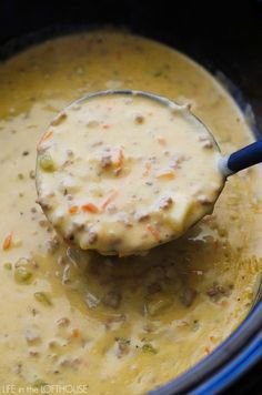 a ladle full of soup is being stirred in the slow cooker