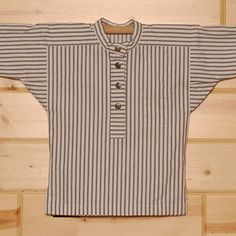 an old striped shirt hanging on a wooden wall