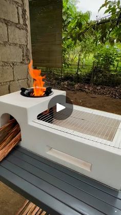 an outdoor bbq grill with flames on the side and wood in front of it