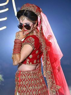 a woman in a red and gold bridal outfit is talking on her cell phone