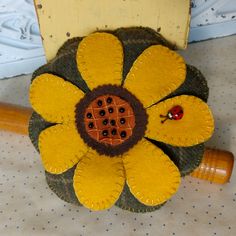 a yellow flower with a ladybug on it sitting next to a wooden stick