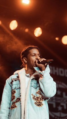 a man standing on top of a stage holding a microphone in his hand and singing