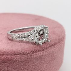 a diamond ring sitting on top of a pink velvet cushioned box with the center stone in