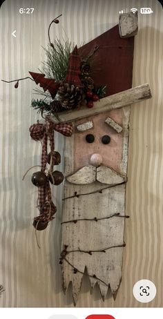 a wooden santa clause with pine cones and berries hanging from it's side on a striped wall