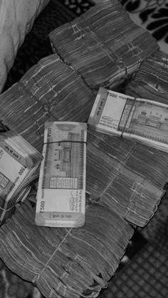 stacks of money sitting on top of a wicker basket next to a pillow in black and white