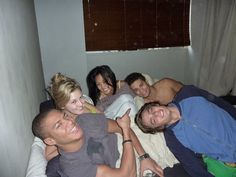 four people are laying on a bed with one person smiling at the camera and another looking up