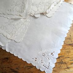 three white embroidered napkins sitting on top of a wooden table