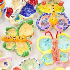 many colorful butterfly shaped cookies on a white tablecloth with candy in the shape of flowers and butterflies