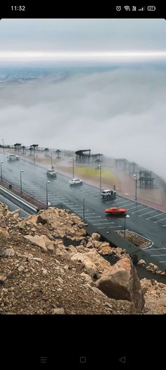 cars are driving down the road on a foggy day with low lying clouds in the background