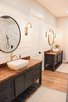 a bathroom with two sinks, mirrors and wooden counter tops on the side of the room