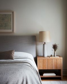 a bed sitting next to a nightstand with a lamp on it's side table