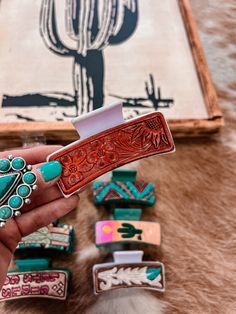 a hand holding a red leather belt with turquoise stones on it and cactus in the background