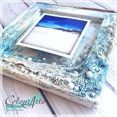 an old photo frame sitting on top of a wooden table with shells and seaweed