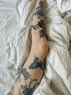 a person with tattoos on their arm laying in bed next to sheets and pillows,