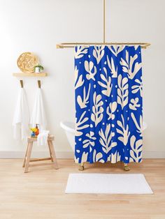 a blue and white floral shower curtain in a bathroom with wooden flooring next to a bathtub