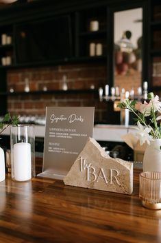 a wooden table topped with white vases filled with flowers and plants next to a sign