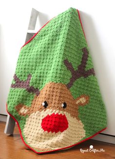 a crocheted christmas blanket with a reindeer on it