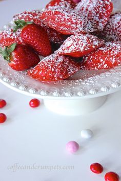 a white plate topped with dessert covered in powdered sugar and strawberries next to candy candies