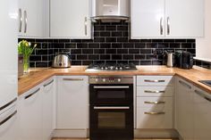 a kitchen with white cabinets and black tile backsplash