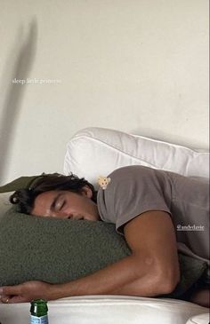 a man sleeping on top of a bed next to a bottle of beer