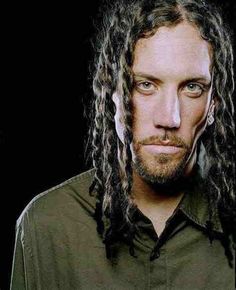 a man with long dreadlocks is looking at the camera while wearing a green shirt