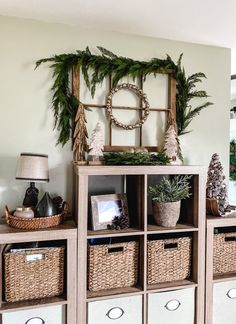 a shelf with baskets and christmas decorations on it in a living room next to a mirror