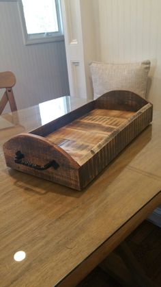 a wooden tray sitting on top of a table next to a pillow and window sill