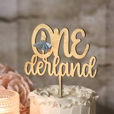 there is a cake with the word one derland on it and flowers in the background